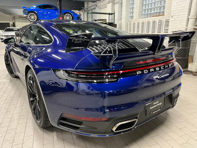 Blue Porsche 911 Carrera from the rear, highlighting its sporty curves and iconic design features.