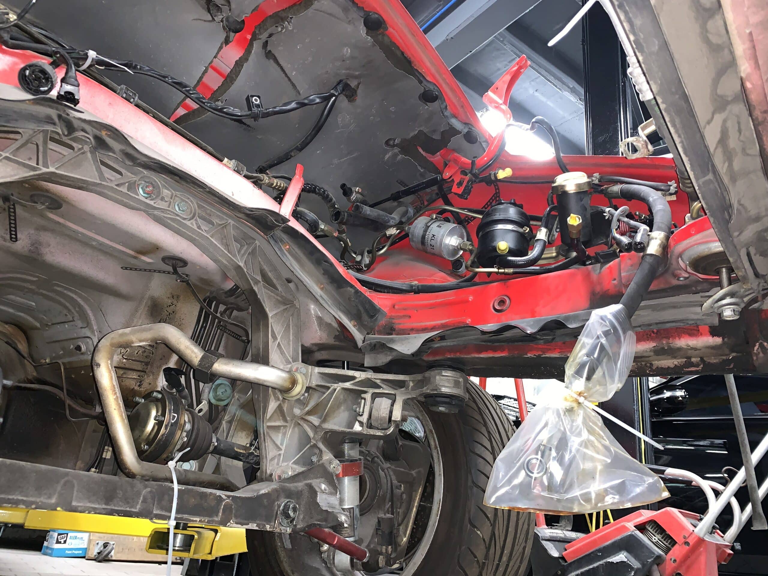 An automobile's engine and exhaust system lie on the ground, highlighting the disassembled parts of the vehicle.