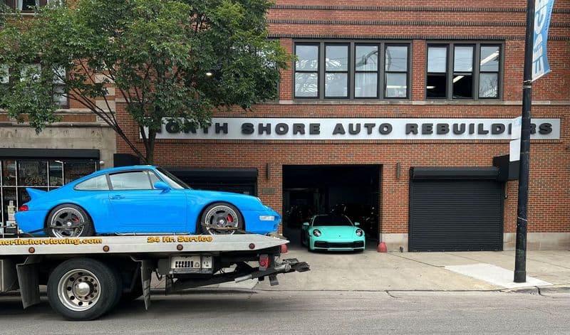 A blue Porsche car is being towed on a flatbed truck, showcasing the vehicle's sleek design and vibrant color.