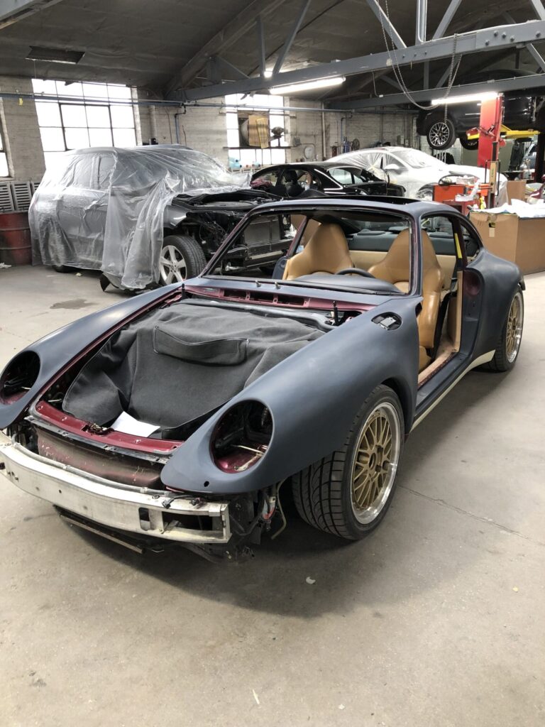 A Porsche 911 Carrera S with its hood open, showcasing the engine and intricate components inside.