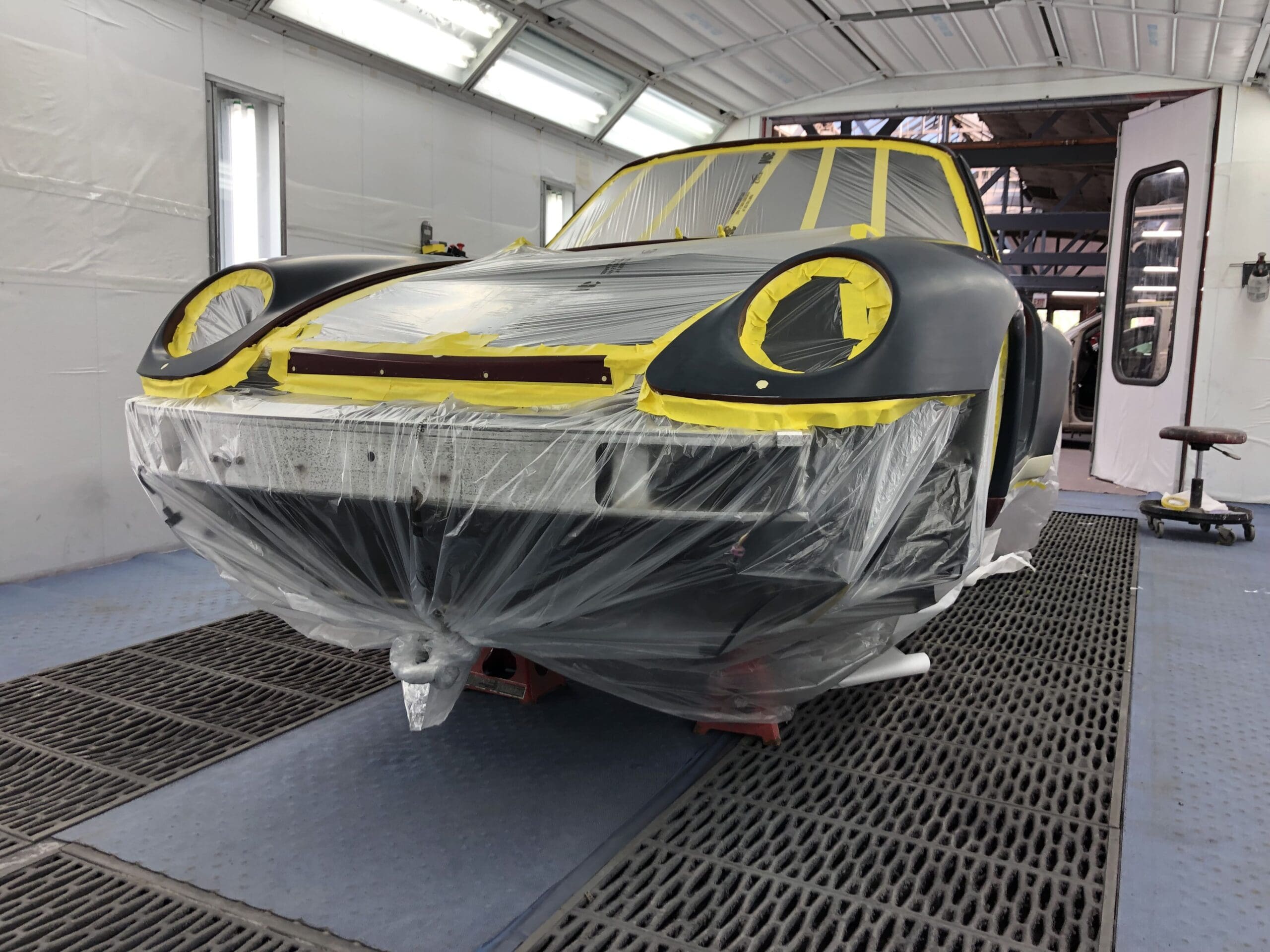 A car in a garage is being painted with bold yellow and black colors, showcasing a creative design process.
