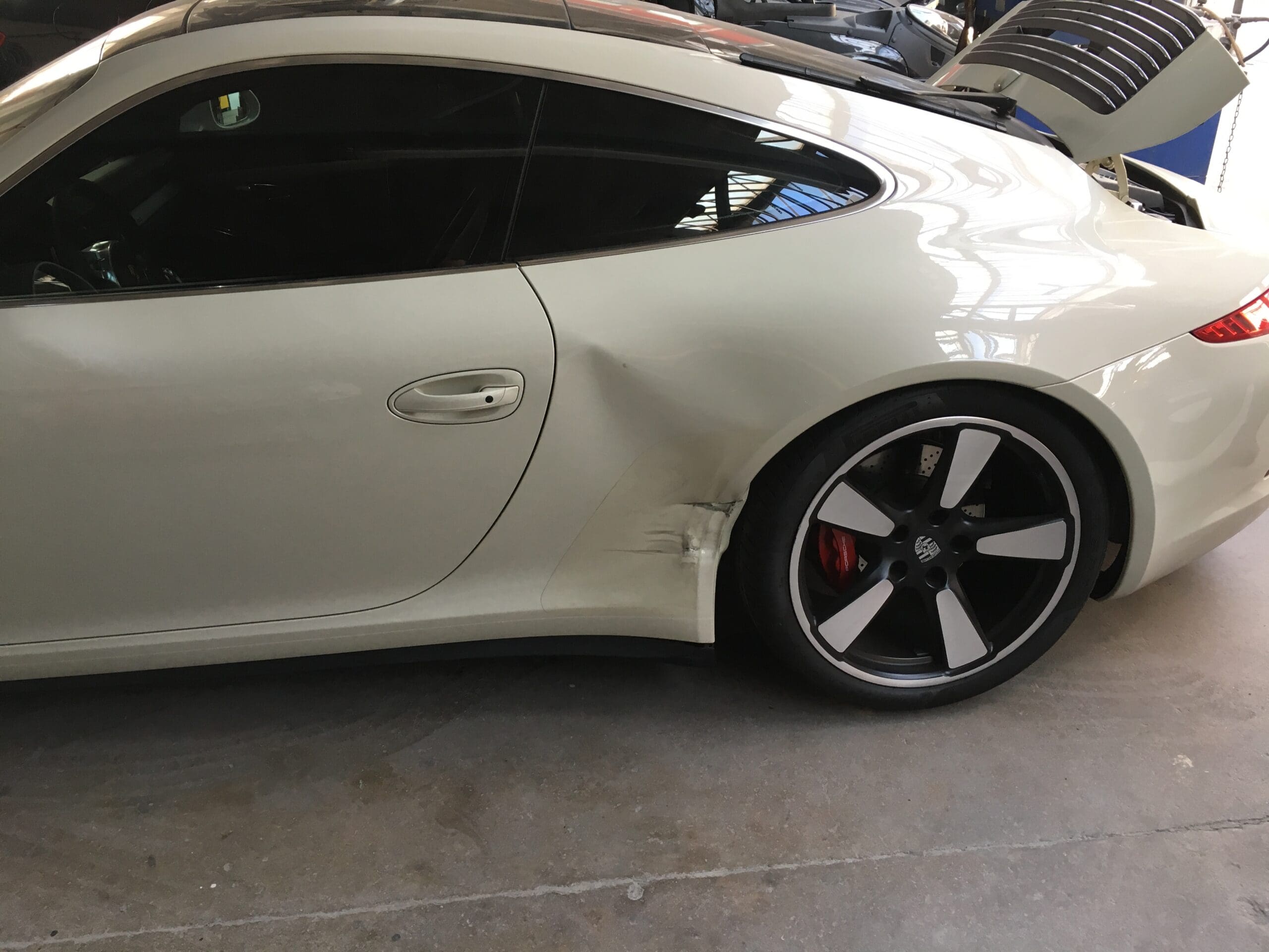 The rear fender of a Porsche showing damage and need for repair