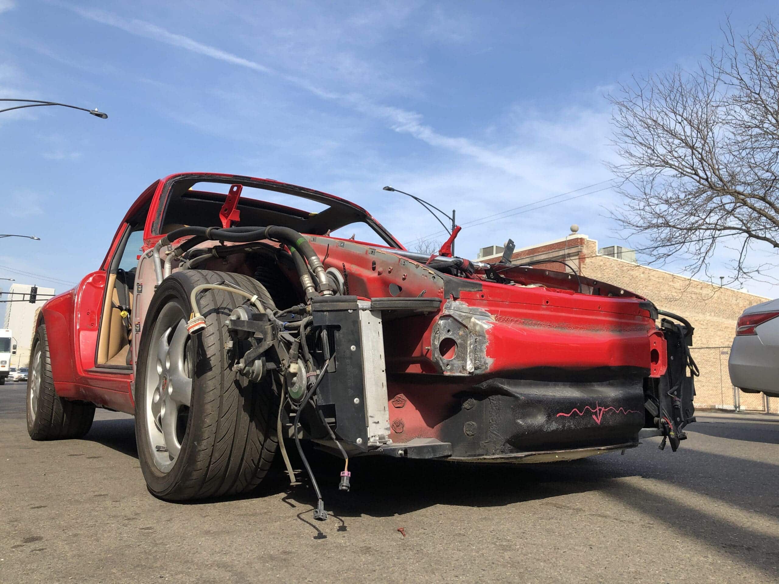 A red car with a heavily damaged front end, showing signs of a recent collision.