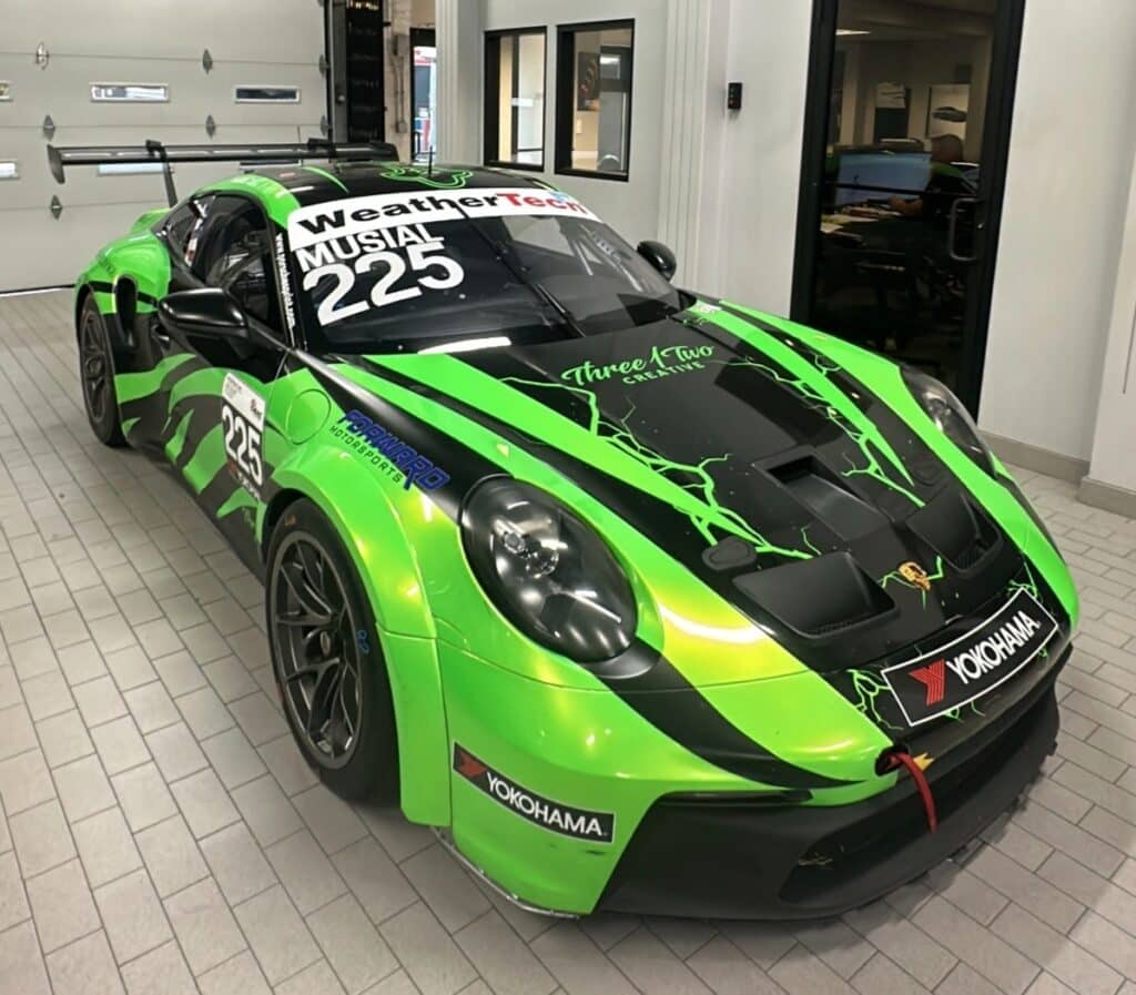 A sleek green and black sports car parked in a well-lit garage, showcasing its modern design and polished finish.